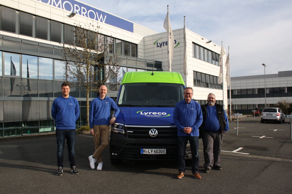 Mitarbeiter aus dem Transport-Bereich von Lyreco vor einem elektrischen Auslieferfahrzeug von Lyreco.